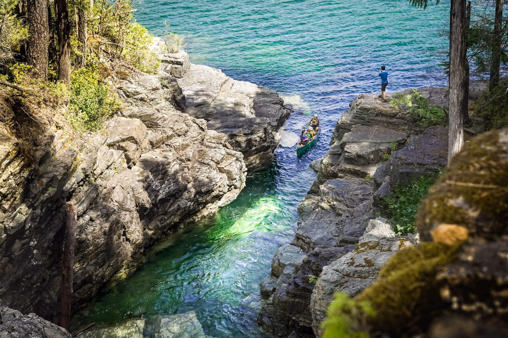 Chris standing in the distance watching a family in canoe paddling towards the water falls