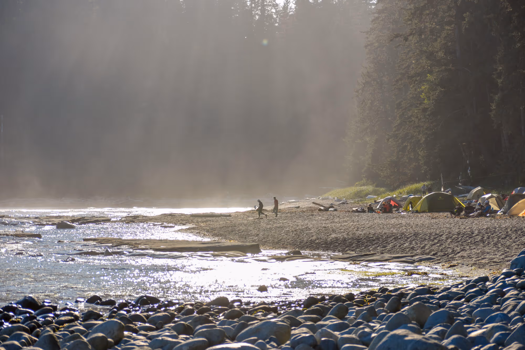 two campers walking towards the water in the morning mist 