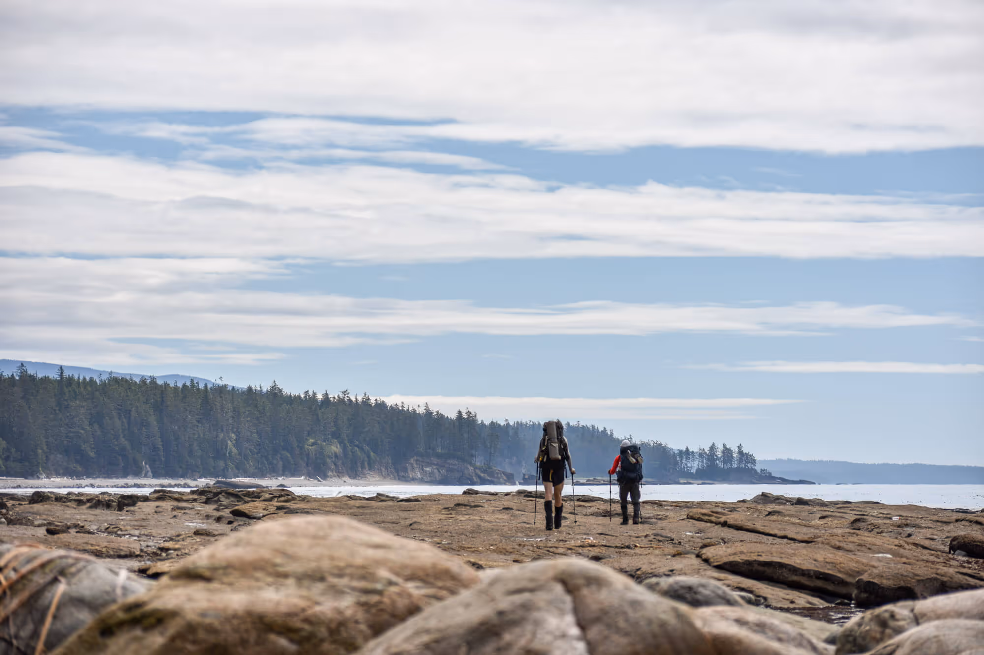 two hikers walking along rock formations on the west coast trail