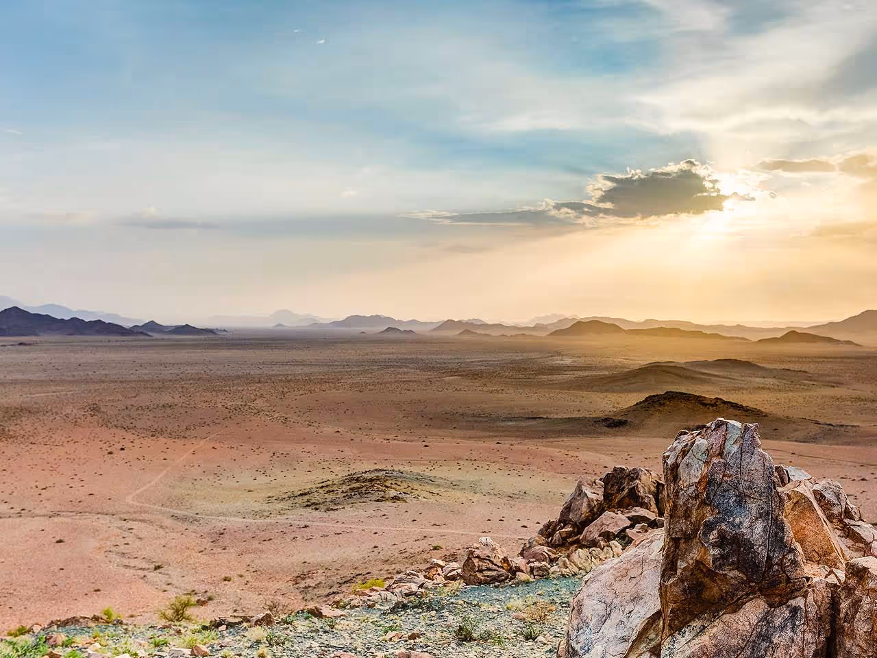 A view out over the endless plains and mountain landscape of the NamibRand Reserve at sunrise. 