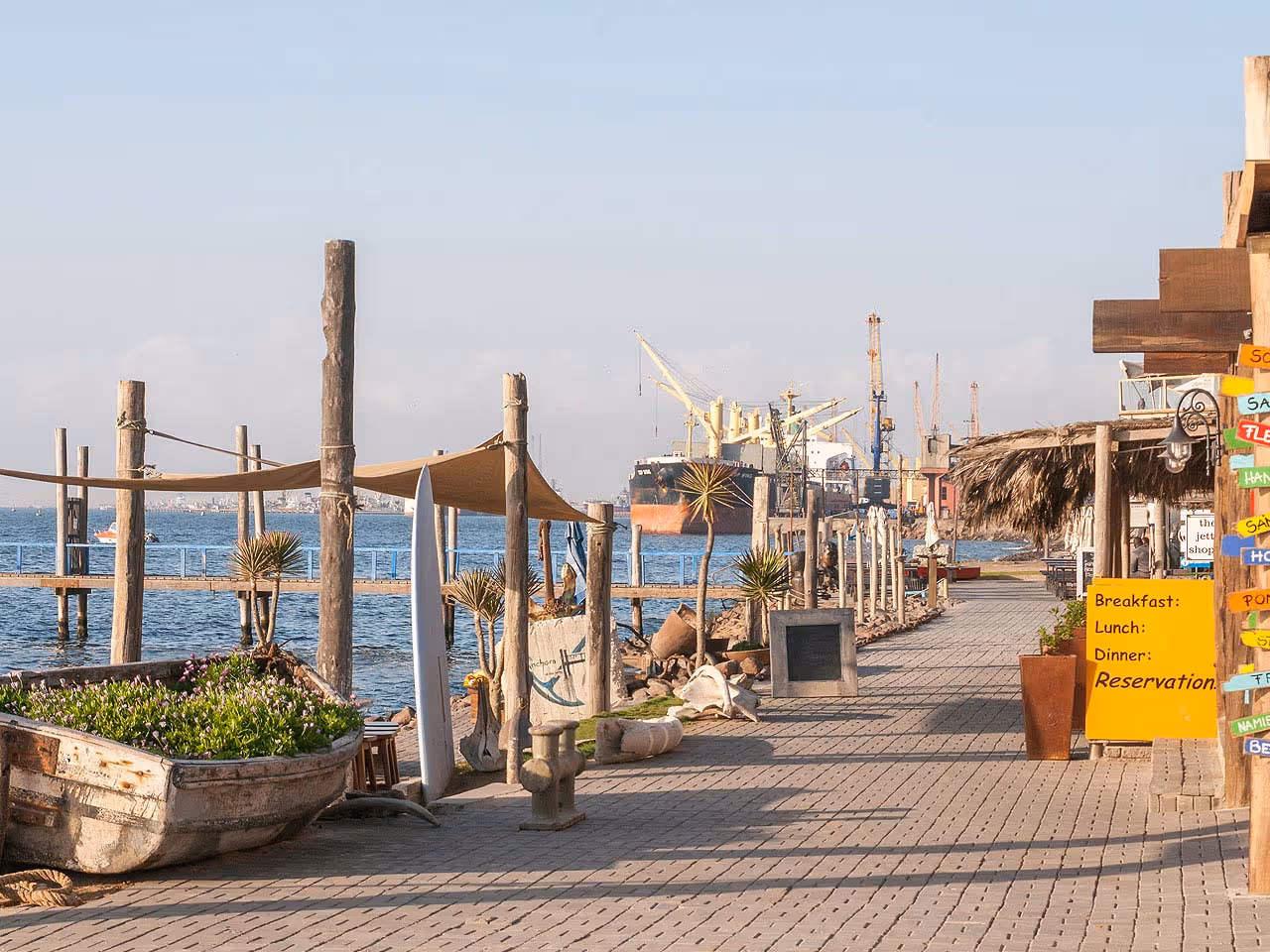 Walvis Bay Waterfront with shops and a large ship in harbour in the background. 