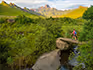 A lady hiking over a bridge at the base of the Drakensberg Mountains. 