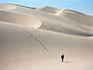 A lone woman walking in the dunes with only her footprints in the sand. 