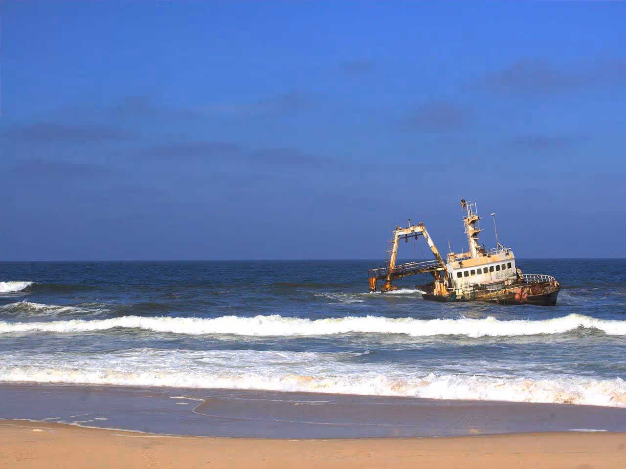A shipwreck in the ocean half submerged as taken from the beach on the Skeleton Coast. 