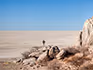 A man standing on a rock looking out over the endless landscape of the Makgadikgadi Pans. 