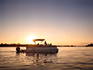 A pontoon boat on a river cruise at sunset.
