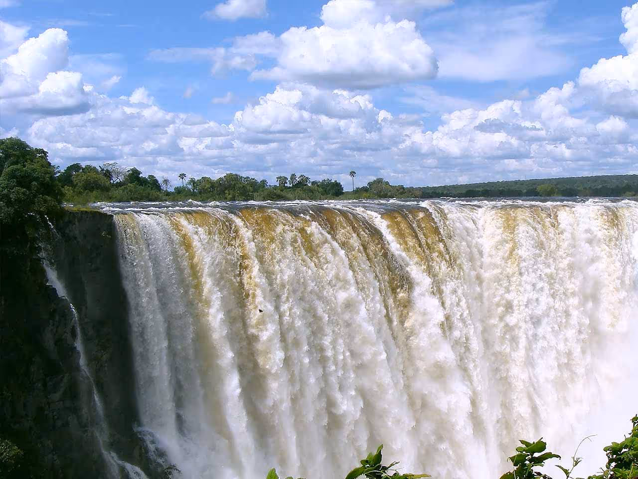 A view of water gushing over the edge of the Victoria Falls in high water season. 