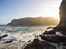 A couple standing on the rocks at shore break at the Knysna Heads on the Garden Route.