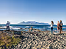 A group of people on the rocky shore of Robben Island looking out at the sea and the distant Table Mountain. 
