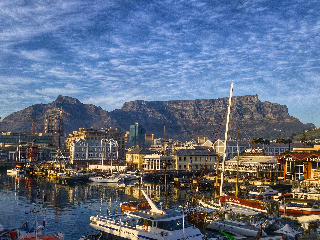 A view over boats on the Cape Town Harbour at the waterfront with Table Mountain in the distance. 