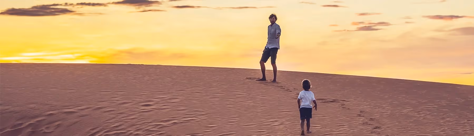 A man and child standing amidst the iconic dunes of Namibia.