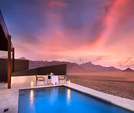 A view of the magnificent sunset at Sossusvlei Desert Lodge over the plunge pool and a private dinner setting. 