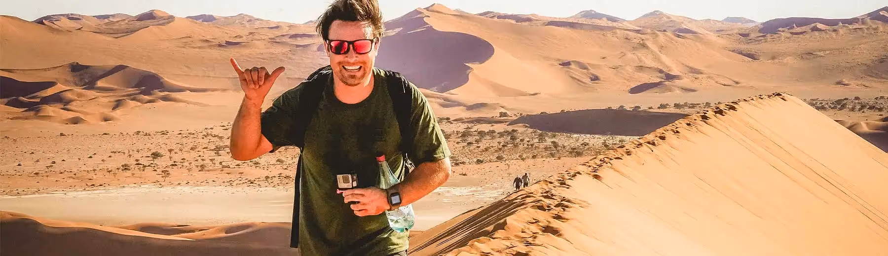 Namibian adventure: A man atop a sand dune, embracing the vast beauty of the desert landscape under the African sun.
