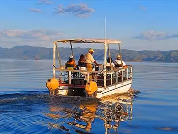 A safari boat on a cruise on the river with distant mountains. 