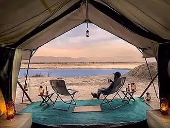 A view out from inside a tent where a man sits enjoying coffee overlooking the river and floodplains. 