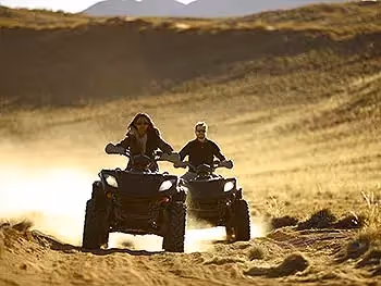 Two people on quad bikes on a sand track in the Namib Desert. 