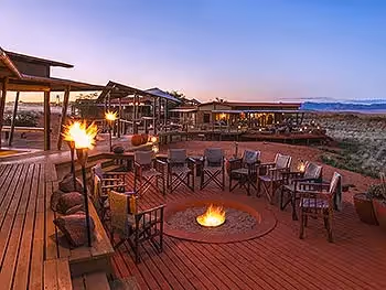 View of the fire pit, deck and main area of Wolwedans Dunes Lodge at dusk.