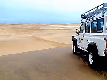 4x4 vehicle overlooking the endless sand dunes of the Namibian coast experienced on a cruise ship shore excursion.