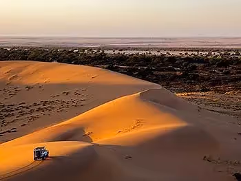 An aerial view of a land cruiser on a sand dune of the Namib Desert overlooking the dry Swakopmund riverbed.