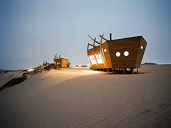 Shipwreck Lodge cabins on the sand dunes of the Skeleton Coast at dusk.