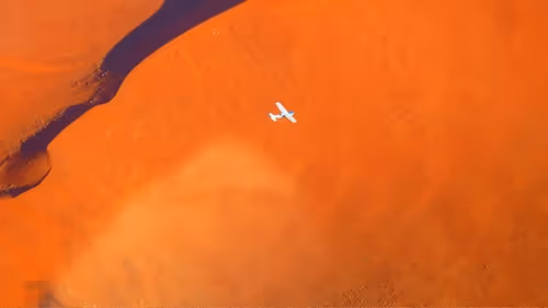 From above, a light aircraft soars over the iconic Sossusvlei dunes, revealing the expanse of Namibia's desert.