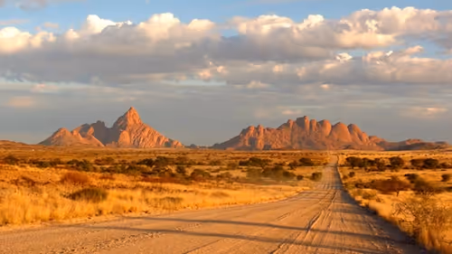 A dusty road winds through the untamed wilderness of Namibia.