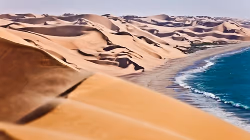 A panoramic view of where the towering sand dunes meet the ocean on the Skeleton Coast of Namibia. 