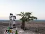 Guides viewing the vast savannah of Botswana’s Tuli Block, with a sundowner drinks set up on the rocks at sunset.