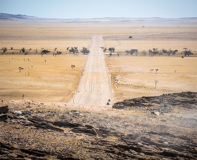 Long gravel road across Namibia’s open plains on a self-drive safari