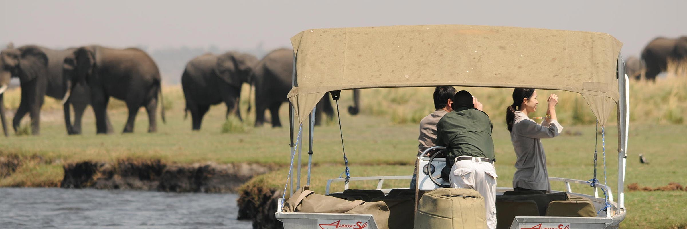 Boot auf dem Chobe-Fluss mit dem Sprühnebel der Victoriafälle im Hintergrund.