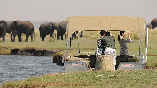 Boot auf dem Chobe-Fluss mit dem Sprühnebel der Victoriafälle im Hintergrund.