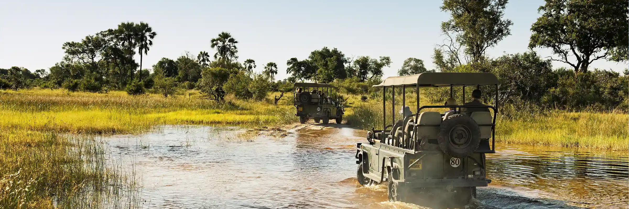 Safari-Fahrzeuge navigieren durch die Wasserwege des Okavango-Deltas.