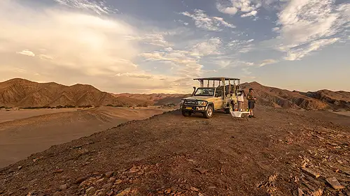 Hot air balloon floats peacefully over the stunning landscape of Sossusvlei at sunrise.