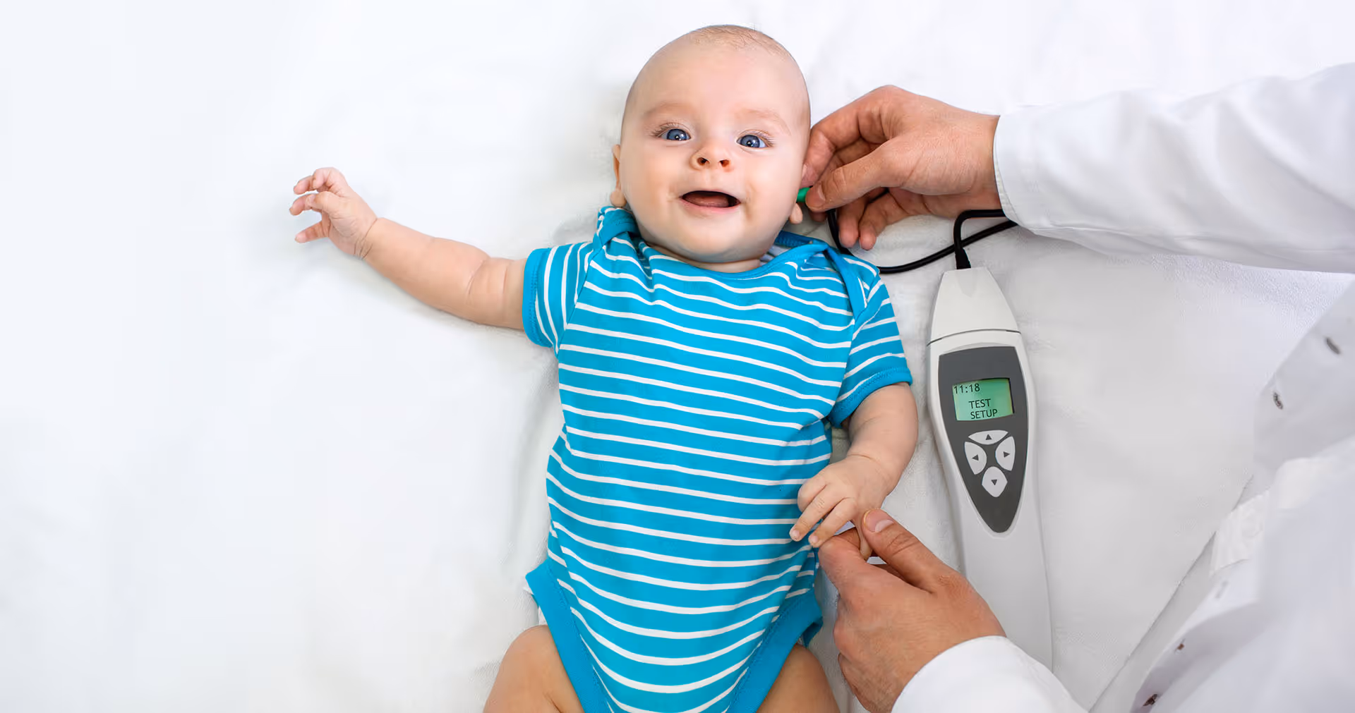 Baby / Säugling im blau-weiß gestreiften Strampler bei der otoakustischen Emmissionstherapie