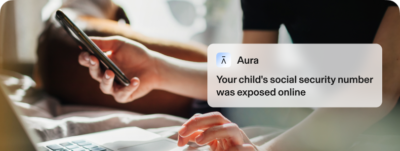 Zoomed-in hands using a laptop and phone. Text reads: Your child’s Social Security number was exposed online.
