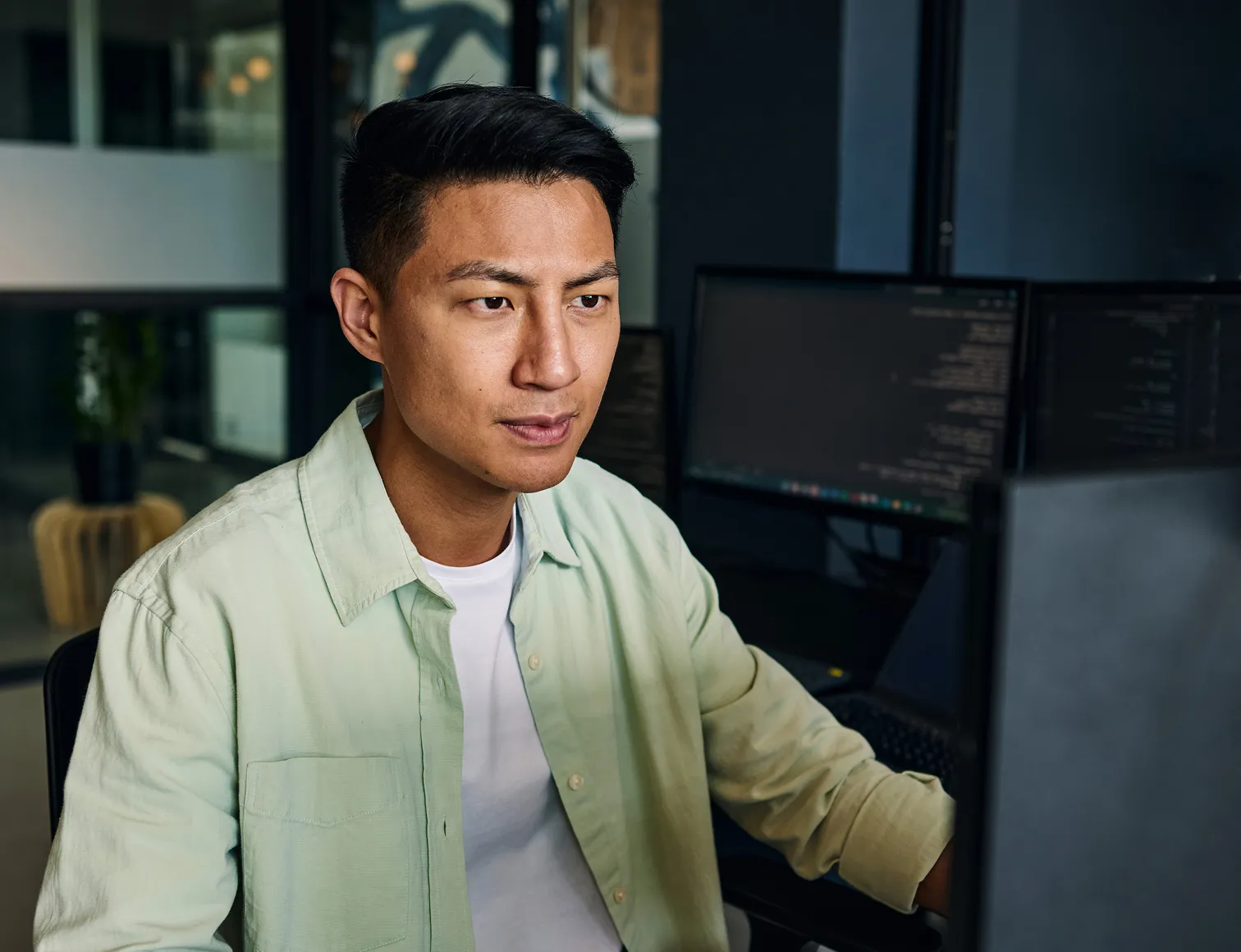 Man in a green collared shirt looking at his computer monitor