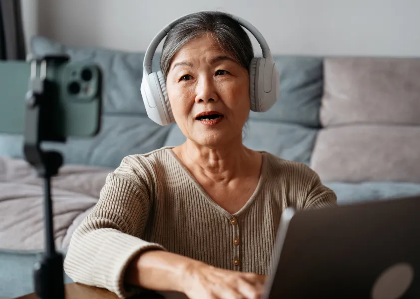 Elderly woman recording content while using a laptop