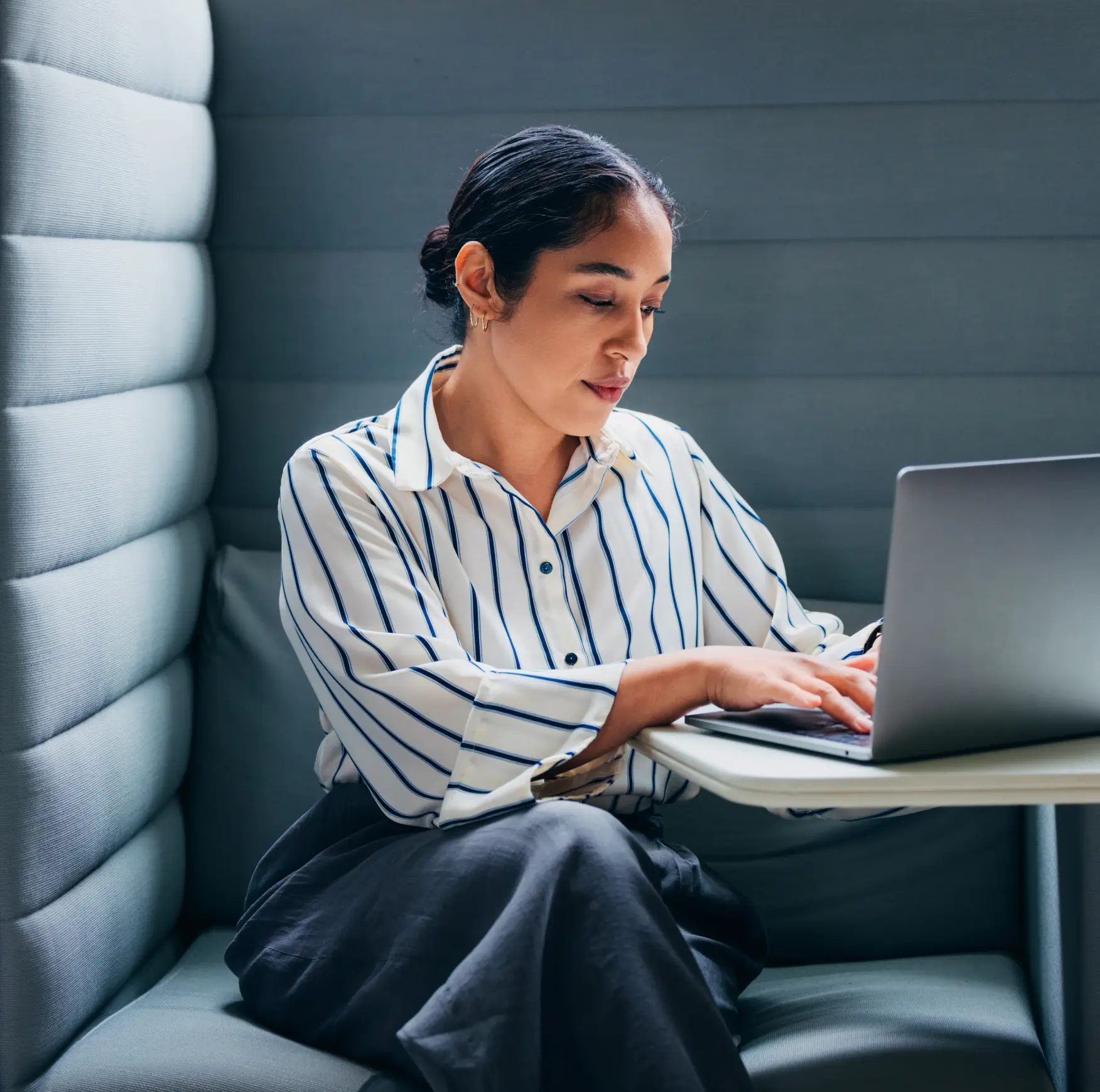 Woman in a striped button up working on her laptop in an office