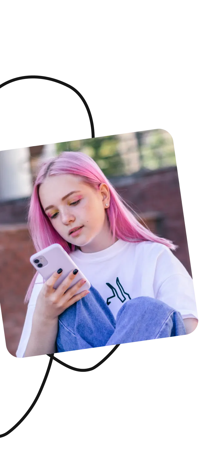 Teen with pink hair looking at a smartphone