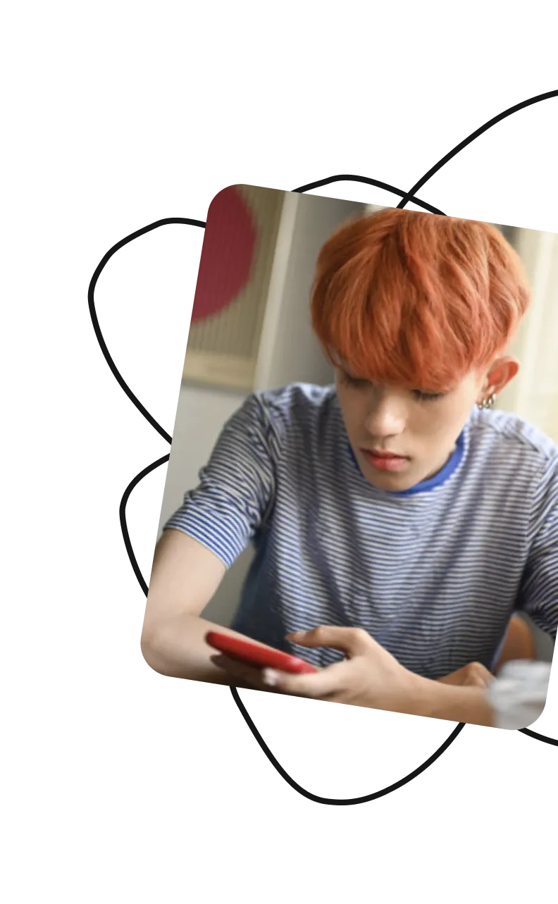 Teen with orange hair looking at a phone indoors