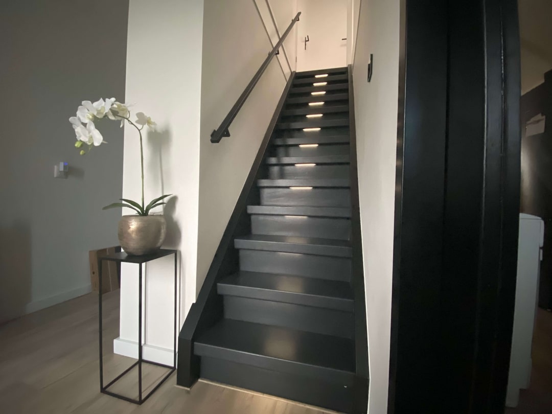 Moderne gerenoveerde trap met verlichting en strakke leuning.