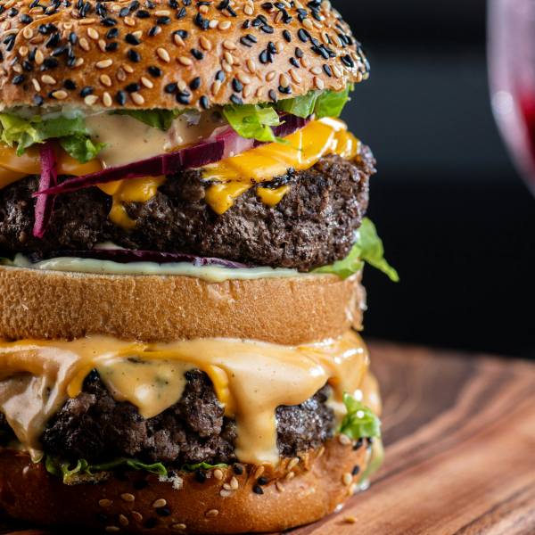 Close-up of a gourmet double cheeseburger with a sesame seed bun, perfect for food lovers.