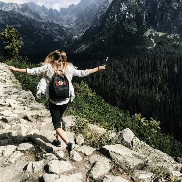 Woman hikes along rocky path in Vysoké Tatry, Slovakia. Embracing nature and freedom.
