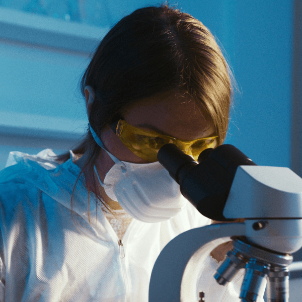 A female scientist examines a sample using a microscope in a laboratory setting.