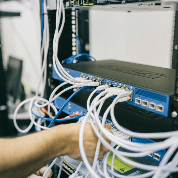 An IT professional configuring network cables in a server rack, focusing on Ethernet connections.