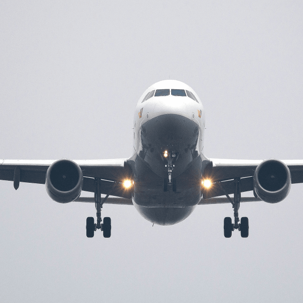 A commercial airliner captured head-on, preparing to land against a cloudy sky.