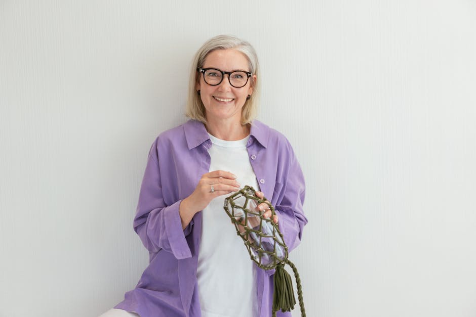 A cheerful senior woman holding a handcrafted decoration with a bright smile.