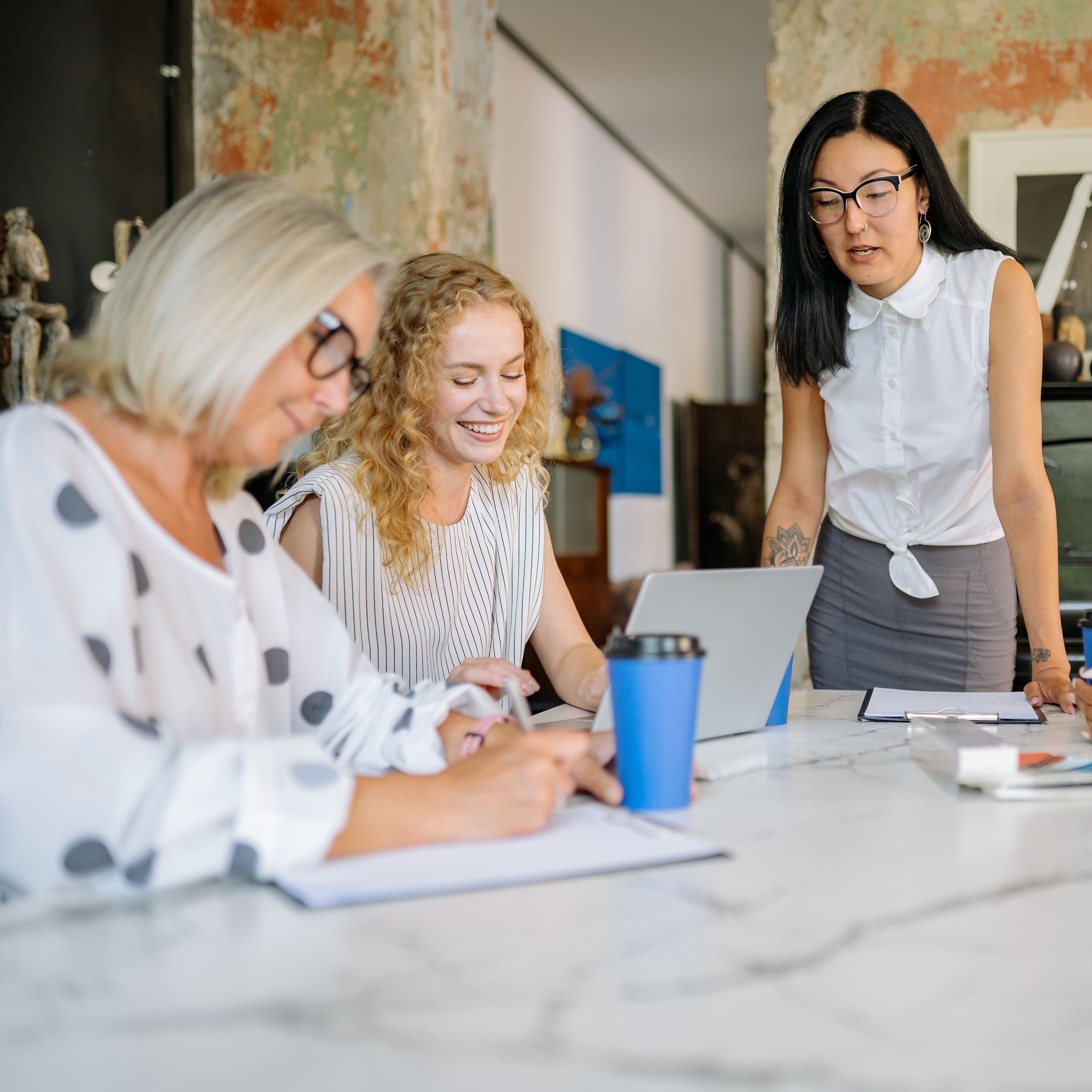 Three women in an office reviewing papers together.