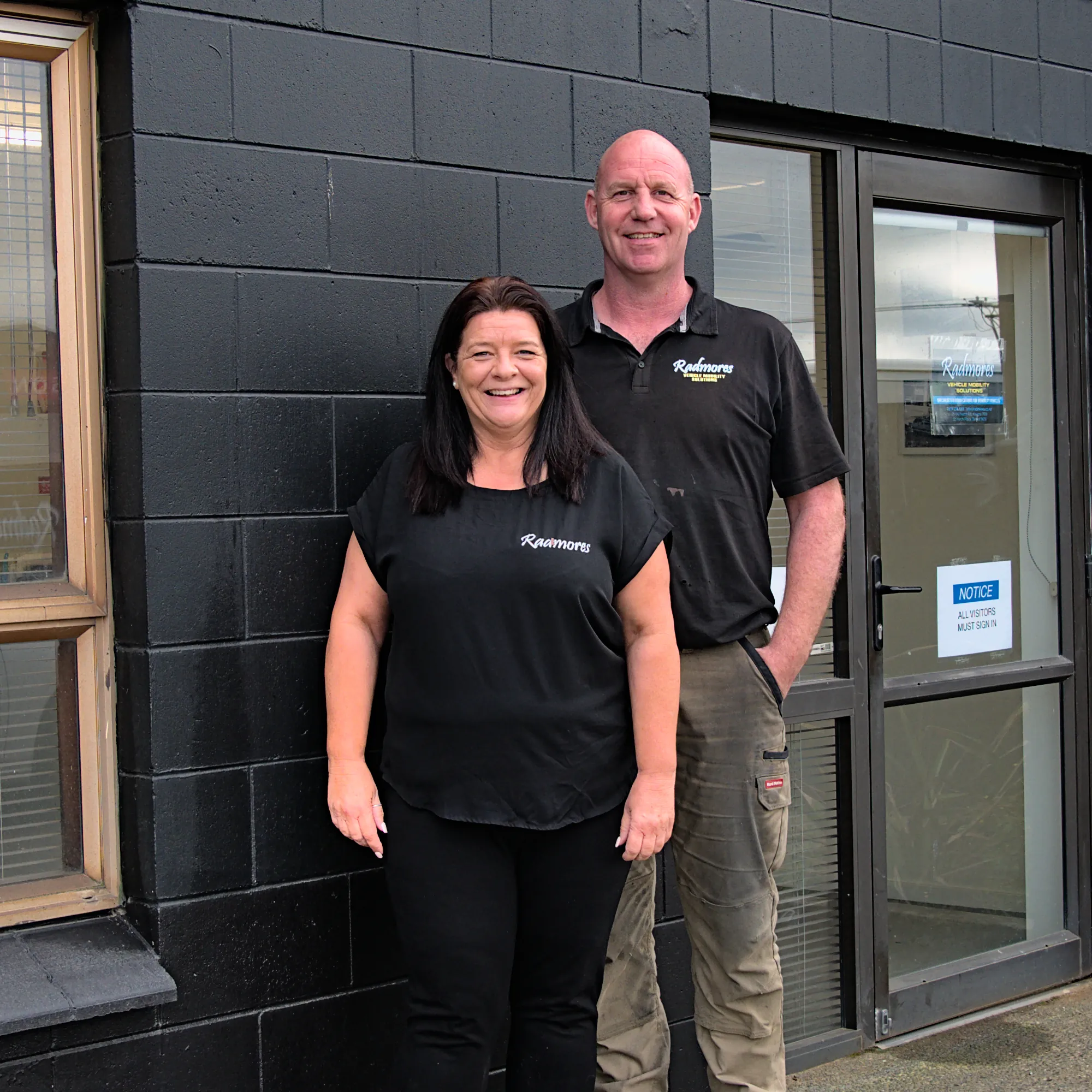 A picture of Conrad and Cherie standing outside the front door to their workshop.