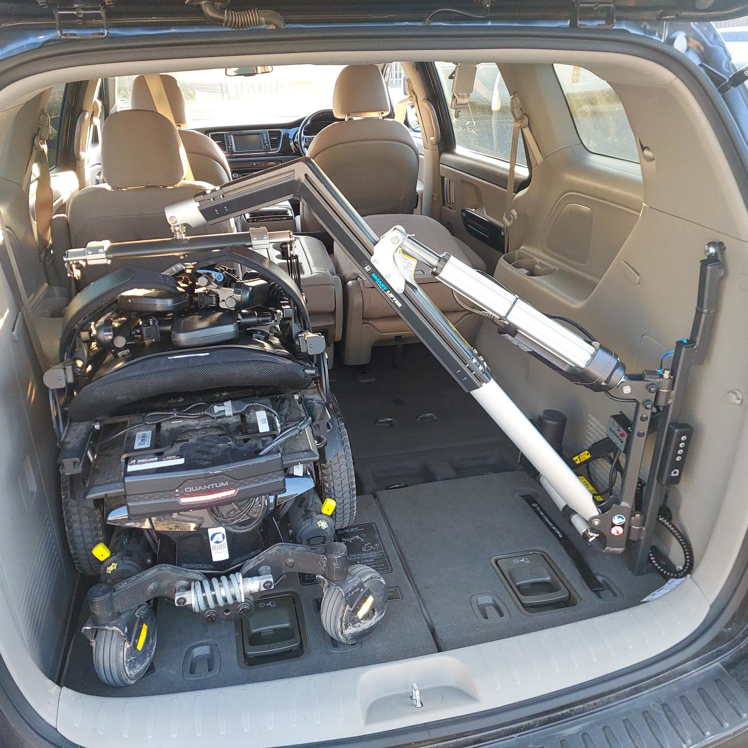 A mobility scooter attached to a vehicle hoist that has been installed in to the rear of a vehicle.